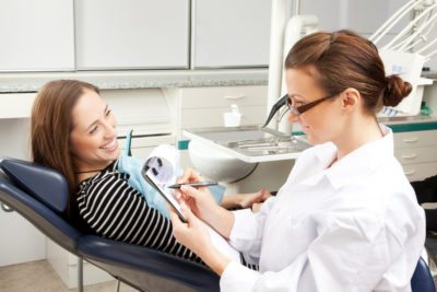 Female dentist in dental office talking with female patient stock photo