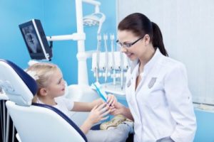 Cute little girl sitting on dental chair and having dental treatment stock photo