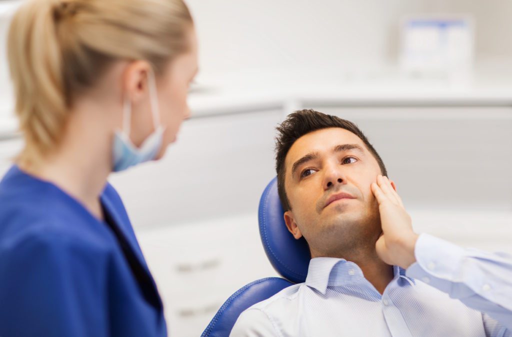 male patient with toothache complaining to female dentist at dental clinic office stock photo