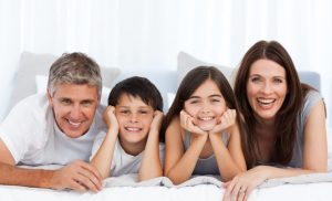 Happy family looking at the camera on their bed stock photo