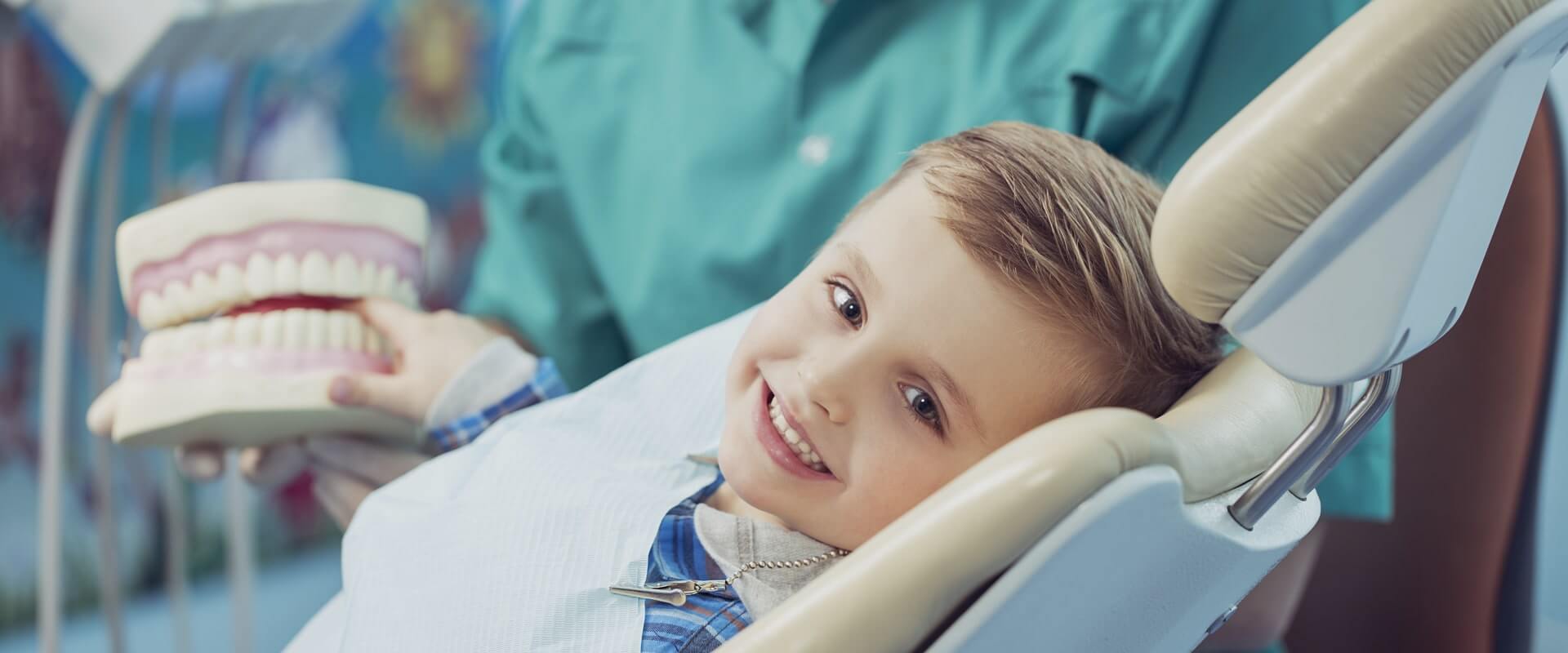 happy boy after the doctor at the clinic, holding a dental jaw in her hands stock photo