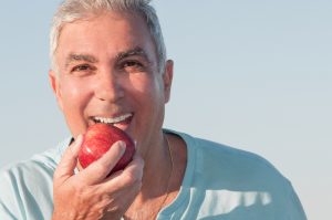 Portrait of a mature man about to eat a red apple stock photo